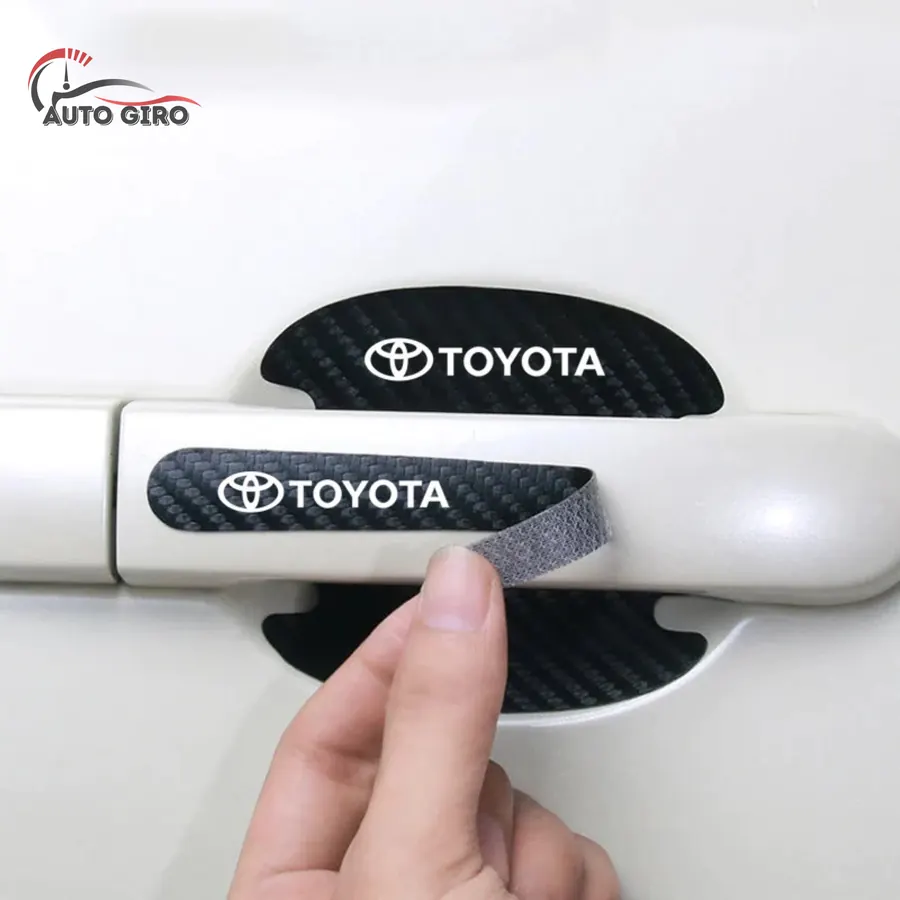 Mão aplicando o protetor de puxador Toyota em fibra de carbono, com a concha já colada