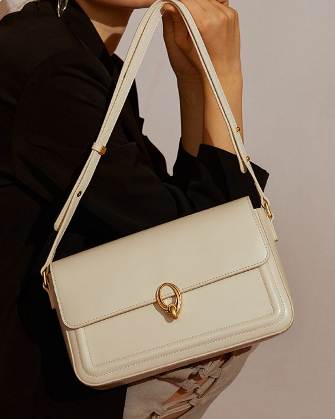 Bolsa feminina de couro, estilo retrô, com detalhes em ferragens douradas e alça ajustável, modelo usando uma bolsa branco marfim